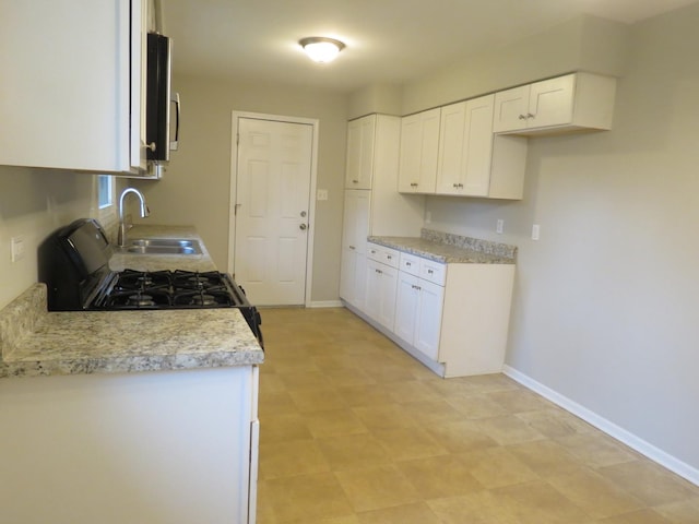 kitchen with black range with gas stovetop, white cabinetry, and sink