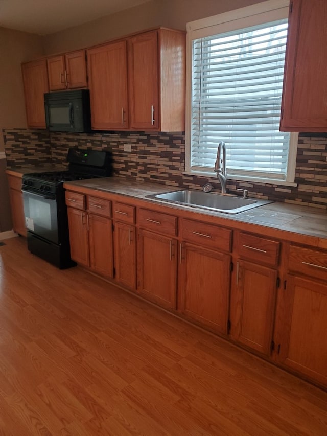 kitchen featuring black appliances, plenty of natural light, sink, and light hardwood / wood-style flooring