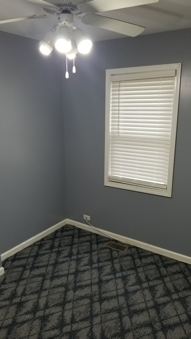 unfurnished room with ceiling fan and dark carpet