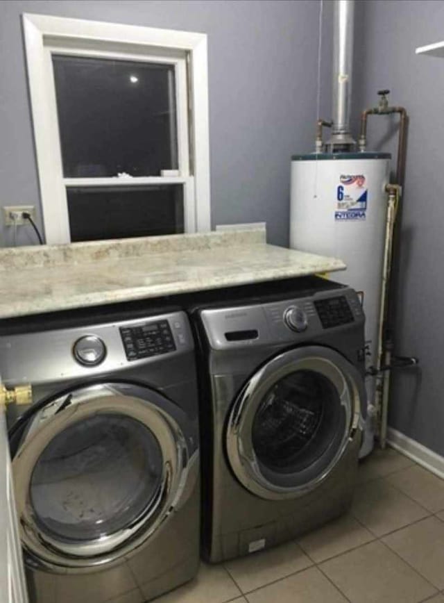 laundry area with light tile patterned floors, gas water heater, and washing machine and clothes dryer