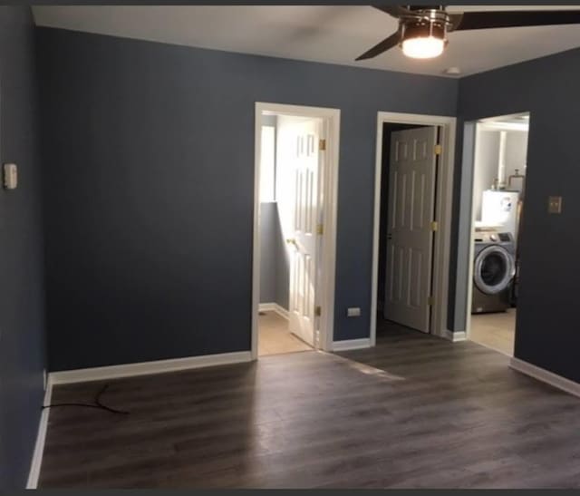 spare room featuring washer / clothes dryer, ceiling fan, and dark wood-type flooring