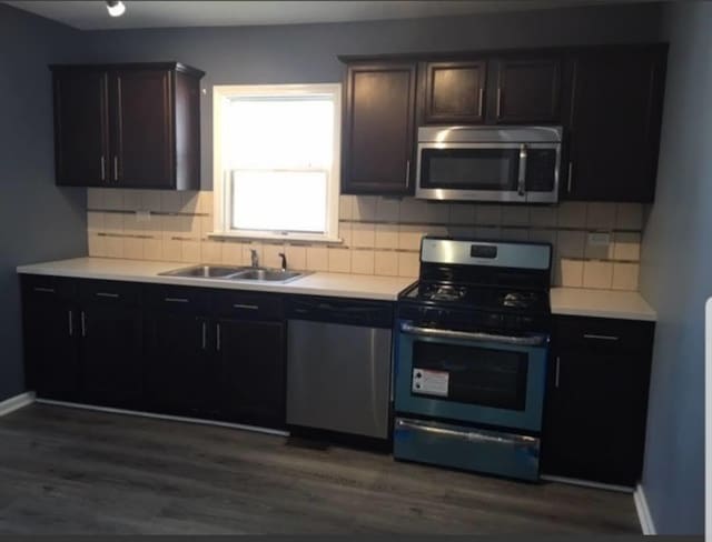 kitchen with backsplash, sink, dark brown cabinets, dark hardwood / wood-style flooring, and stainless steel appliances