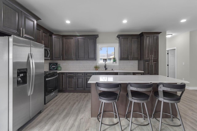 kitchen with decorative backsplash, stainless steel appliances, a kitchen island, and sink