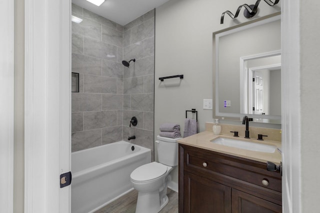 full bathroom with tiled shower / bath combo, toilet, wood-type flooring, and vanity