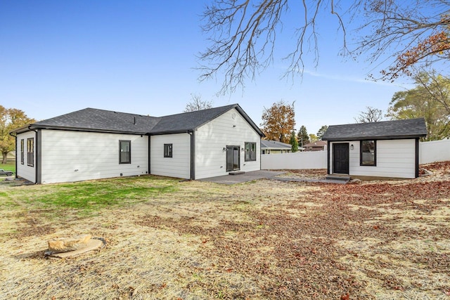 rear view of house featuring an outdoor structure and a lawn