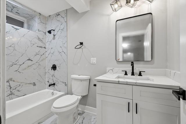 full bathroom featuring vanity, tiled shower / bath combo, and toilet