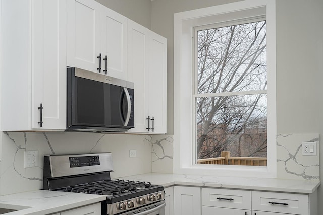 kitchen featuring light stone counters, white cabinetry, backsplash, and appliances with stainless steel finishes