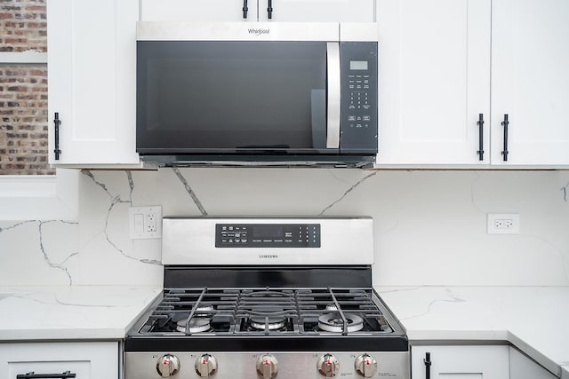 kitchen featuring white cabinets, stainless steel appliances, tasteful backsplash, and light stone countertops