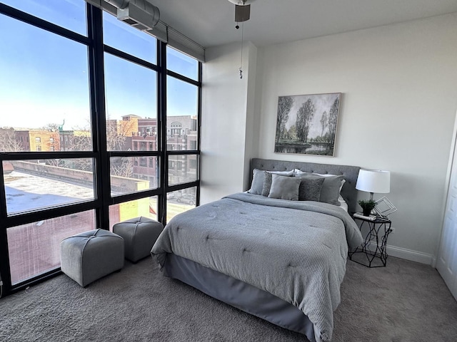 carpeted bedroom featuring a wall of windows and ceiling fan