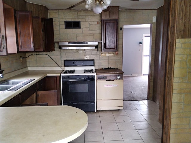 kitchen with gas range oven, dark brown cabinetry, ceiling fan, sink, and light tile patterned floors