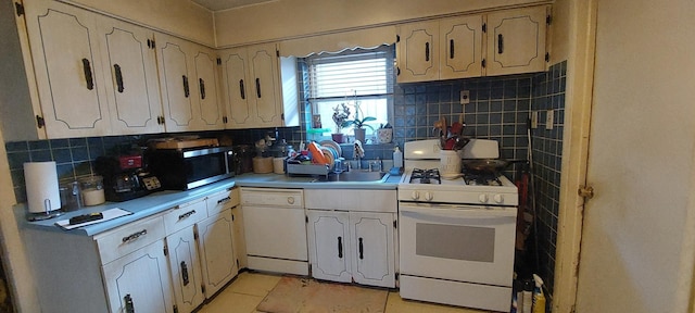 kitchen with white appliances, sink, light tile patterned floors, and tasteful backsplash