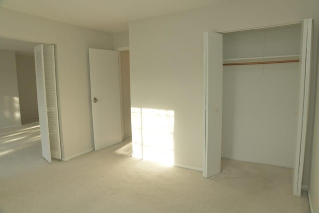 unfurnished bedroom featuring light colored carpet and a closet