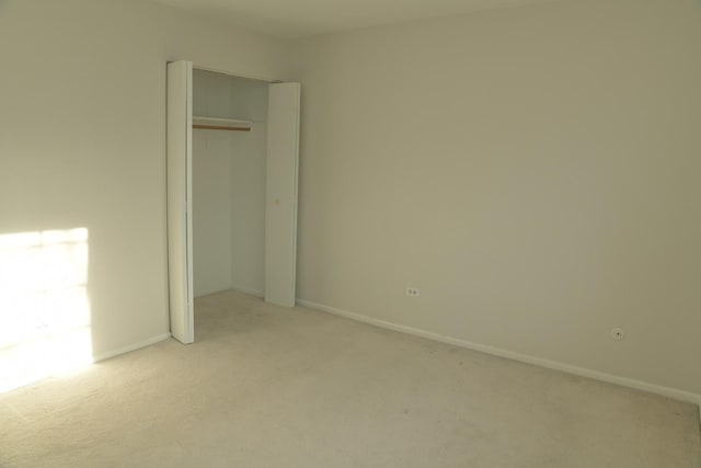 unfurnished bedroom featuring light colored carpet and a closet