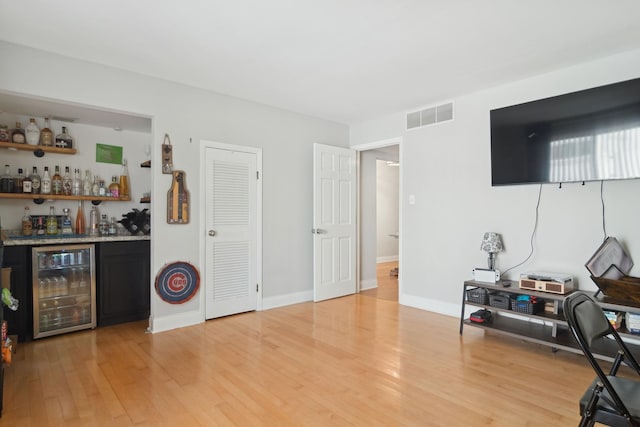 interior space featuring indoor bar, wine cooler, and light hardwood / wood-style flooring