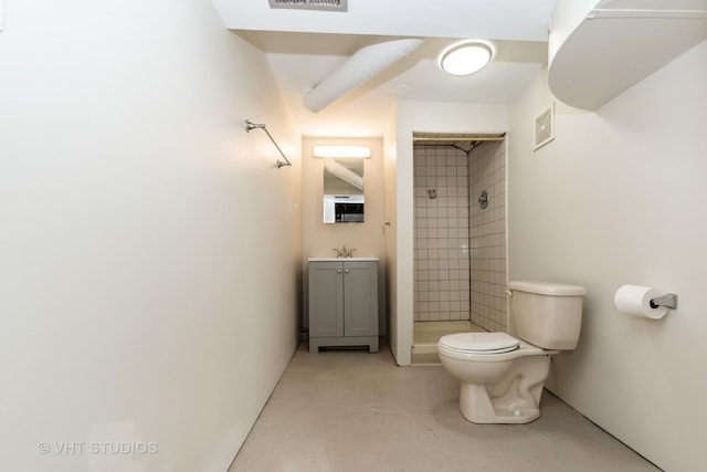 bathroom featuring concrete floors, toilet, vanity, and a tile shower