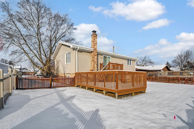 snow covered back of property with a deck