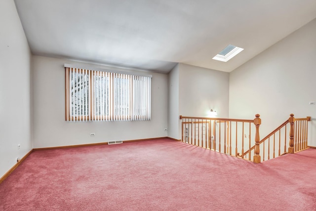 carpeted spare room with vaulted ceiling with skylight