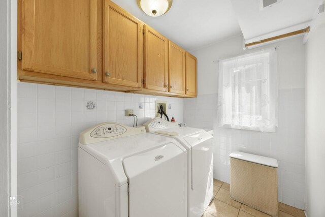 laundry room with light tile patterned flooring, cabinets, independent washer and dryer, and tile walls