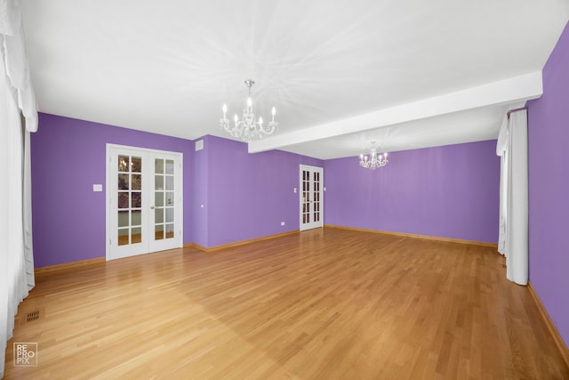 spare room featuring an inviting chandelier, light wood-type flooring, beam ceiling, and french doors