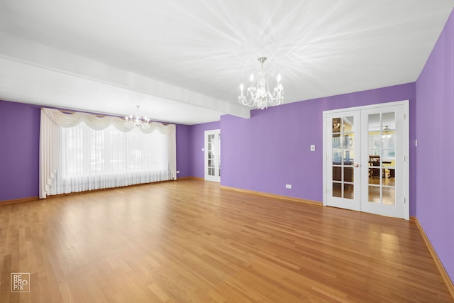 spare room with hardwood / wood-style floors, french doors, a chandelier, and beam ceiling