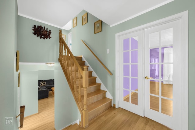 stairs featuring hardwood / wood-style floors, french doors, and ornamental molding