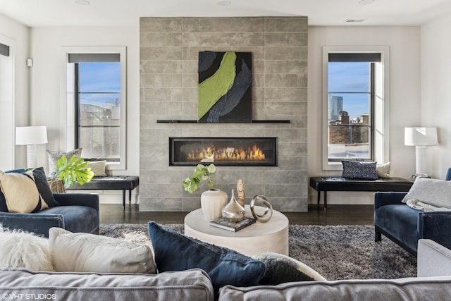 living room featuring dark hardwood / wood-style flooring and a tiled fireplace