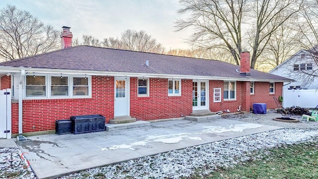 snow covered rear of property with a patio area