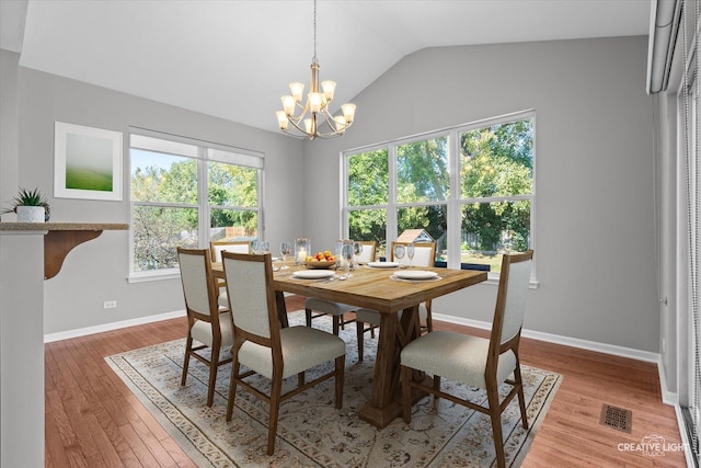 dining room with a chandelier, vaulted ceiling, and hardwood / wood-style flooring