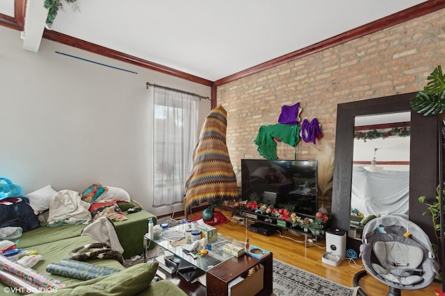 living room featuring hardwood / wood-style flooring, crown molding, and brick wall