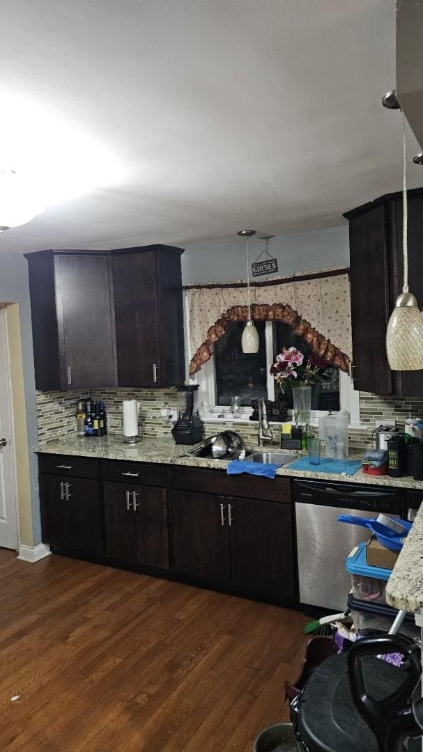 kitchen featuring dark brown cabinetry, dark hardwood / wood-style floors, stainless steel dishwasher, and hanging light fixtures