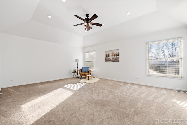 unfurnished room with ceiling fan, vaulted ceiling, light carpet, and a tray ceiling