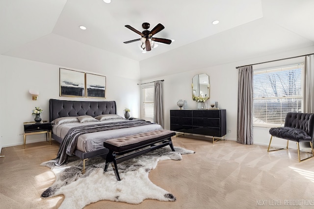 carpeted bedroom featuring multiple windows, vaulted ceiling, a raised ceiling, and ceiling fan