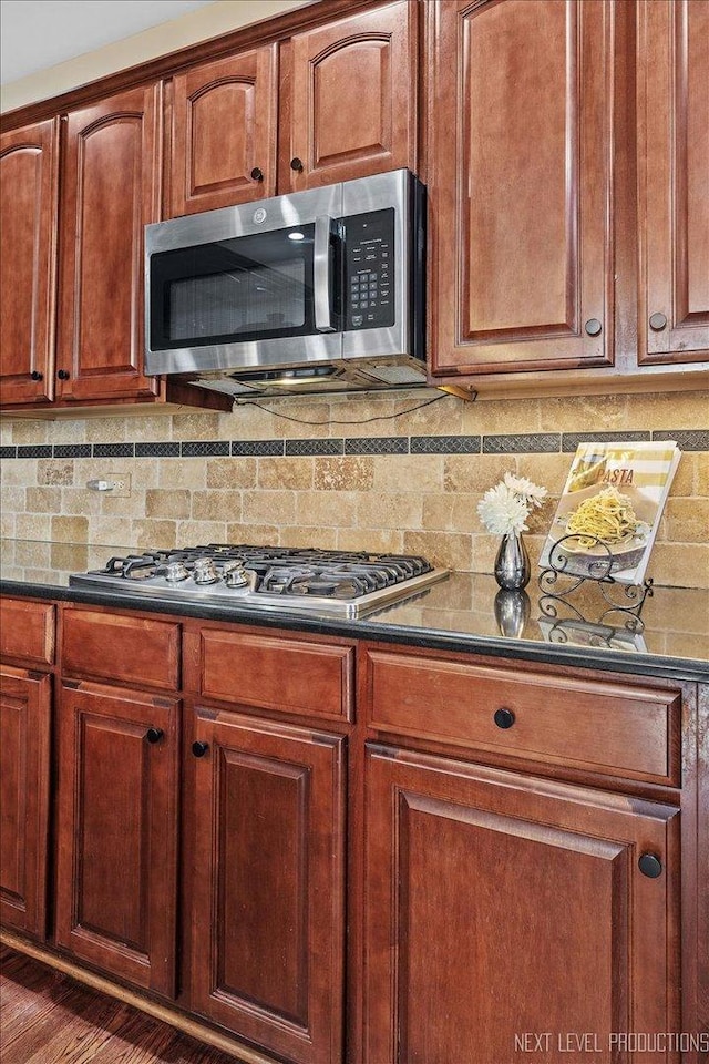 kitchen with dark hardwood / wood-style flooring, backsplash, and stainless steel appliances