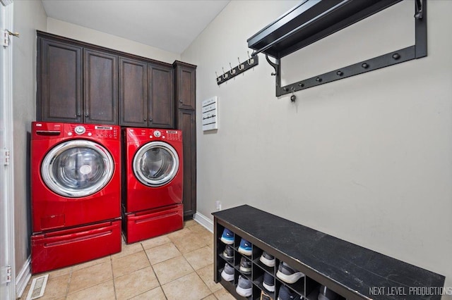 laundry room featuring cabinets, light tile patterned floors, and washing machine and dryer