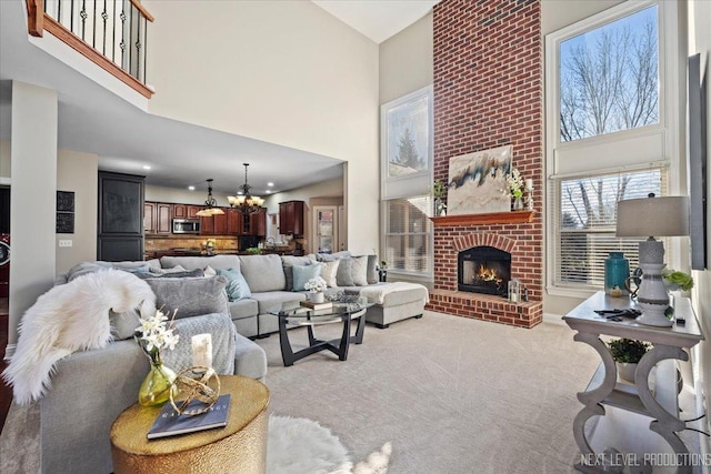 carpeted living room featuring a brick fireplace, a high ceiling, and an inviting chandelier