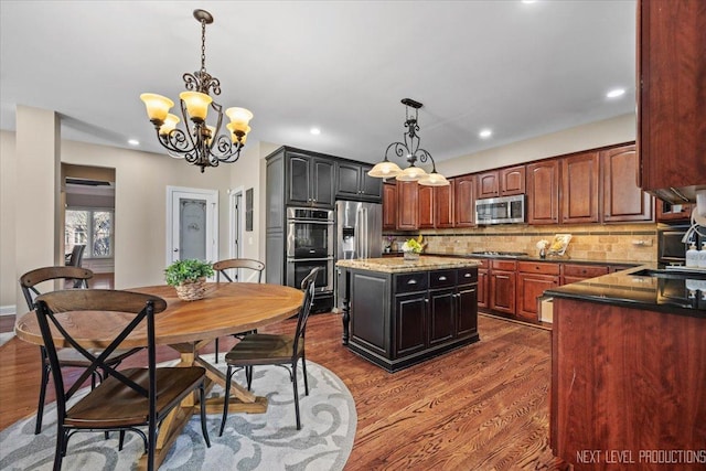 kitchen with a center island, sink, dark hardwood / wood-style floors, tasteful backsplash, and stainless steel appliances