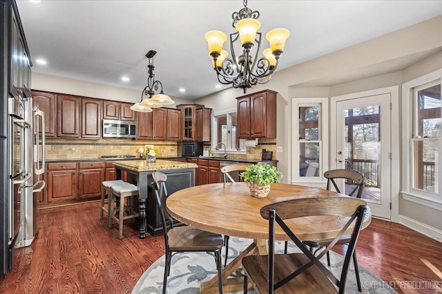 dining space featuring sink, dark wood-type flooring, and an inviting chandelier