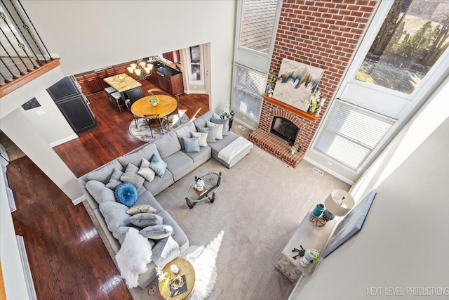 living room featuring a wealth of natural light, a fireplace, a high ceiling, and hardwood / wood-style flooring