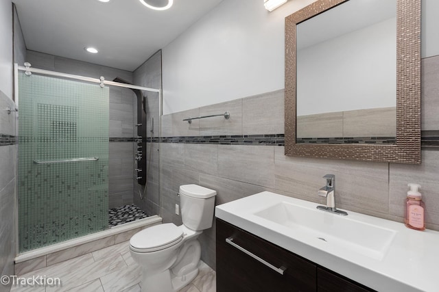 bathroom featuring an enclosed shower, vanity, toilet, and tile walls