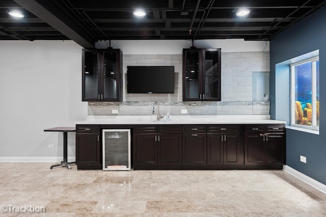 kitchen featuring dark brown cabinets, sink, wine cooler, and tasteful backsplash