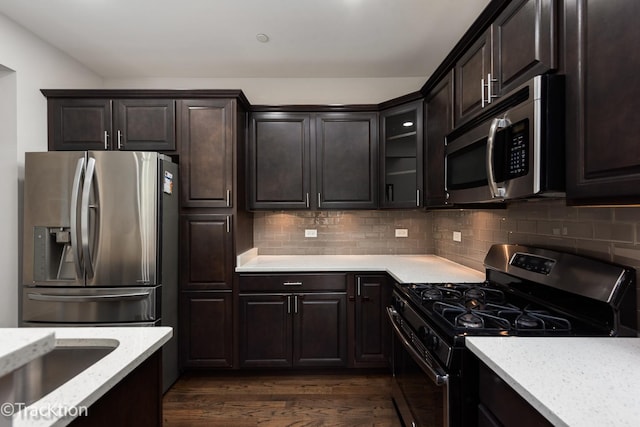 kitchen featuring backsplash, dark wood-type flooring, stainless steel appliances, and dark brown cabinets