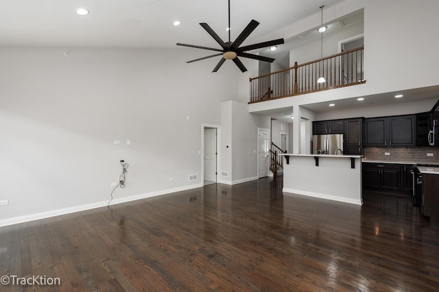 unfurnished living room with high vaulted ceiling, ceiling fan, and dark wood-type flooring