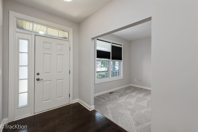 foyer entrance featuring dark carpet