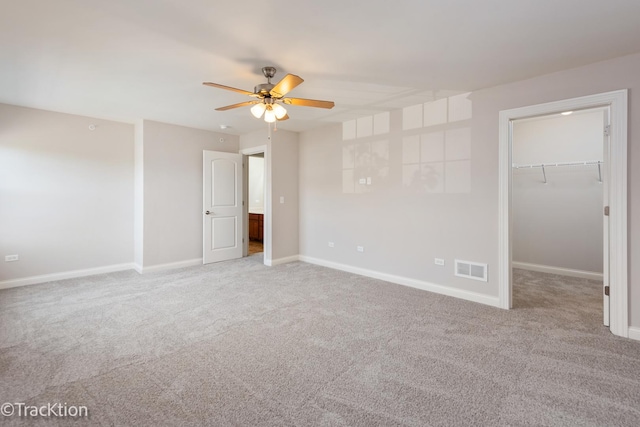 unfurnished bedroom featuring ceiling fan, light colored carpet, a spacious closet, and a closet