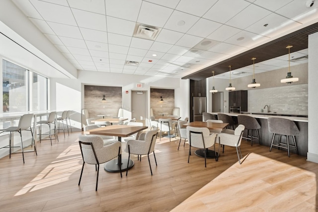 dining area featuring wood-type flooring, a paneled ceiling, and sink