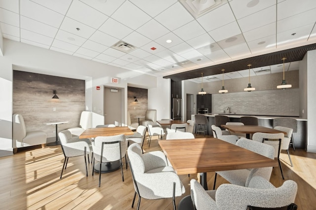 dining space featuring light hardwood / wood-style floors, a drop ceiling, and sink