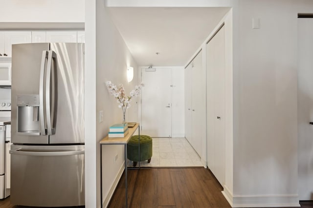 kitchen featuring stainless steel fridge with ice dispenser, hardwood / wood-style floors, white cabinets, and range