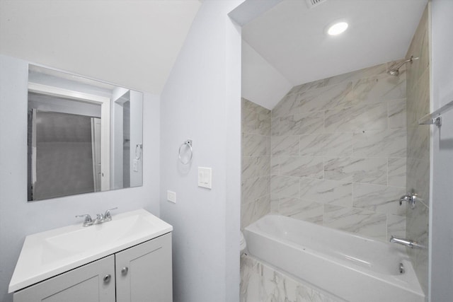 full bathroom with lofted ceiling, vanity, tiled shower / bath combo, and toilet