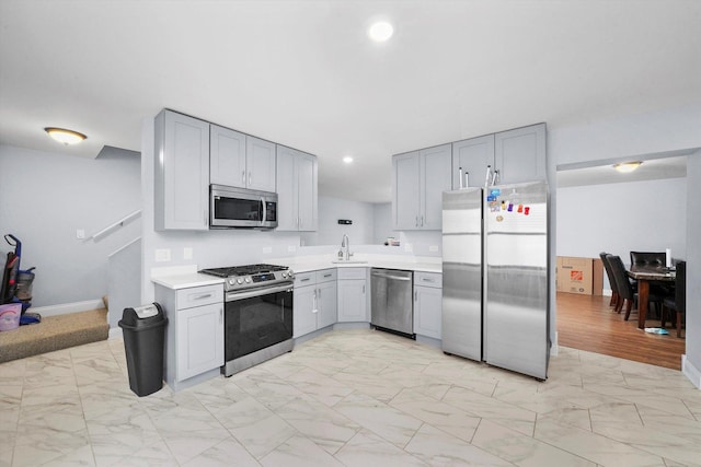 kitchen with stainless steel appliances, gray cabinetry, and sink