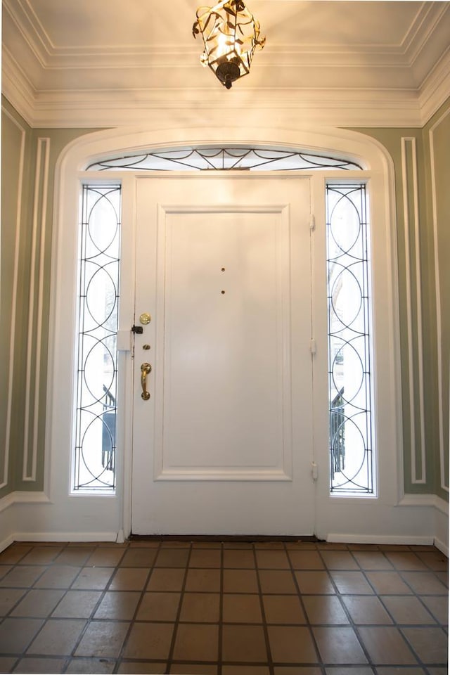 foyer entrance featuring plenty of natural light, dark tile patterned floors, and ornamental molding